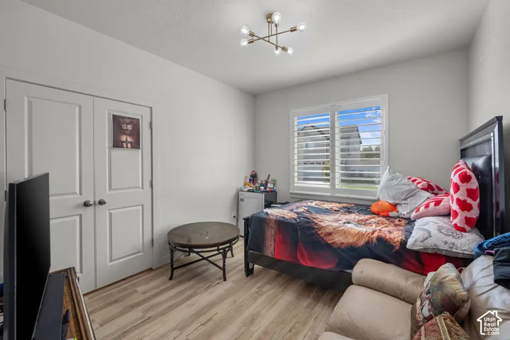 White interior walls, two-panel interior doors, light wood-finish flooring, window with white plantation shutters, and a modern ceiling light fixture