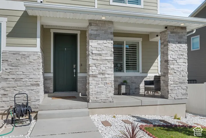 Front entry with stone veneer accents, concrete steps, and a covered porch