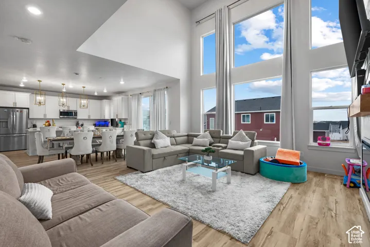 Open-concept living area with soaring ceilings, wood-finish flooring, and large windows providing ample natural light