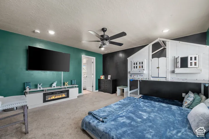 Integrated electric fireplace, ceiling fan with light fixture, recessed lighting, carpeted flooring, and built-in white loft structure
