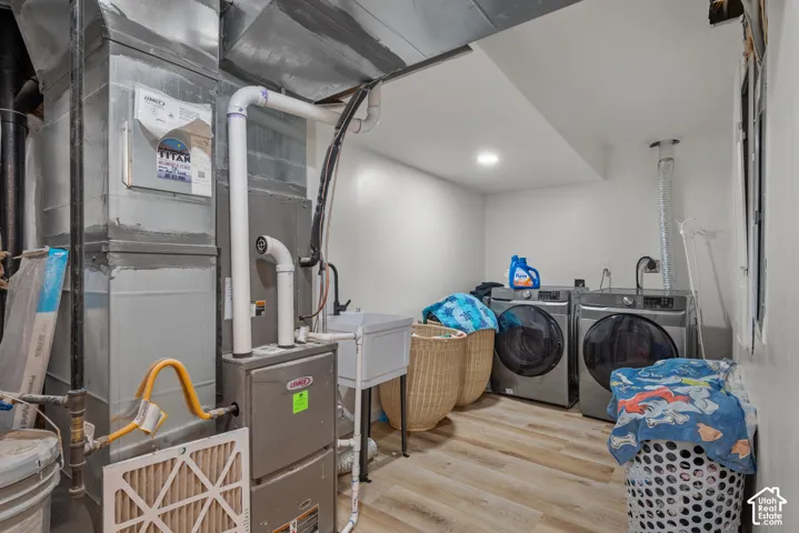 Dedicated laundry area featuring a utility sink, light wood-finish flooring, and recessed ceiling lighting