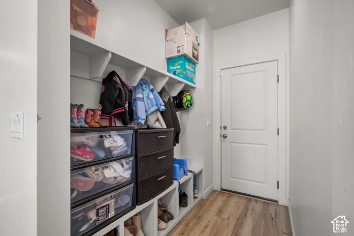 Built-in white shelving, integrated coat hooks, and wood-finish flooring