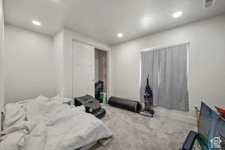 Recessed lighting, light-toned walls, and neutral carpet flooring
