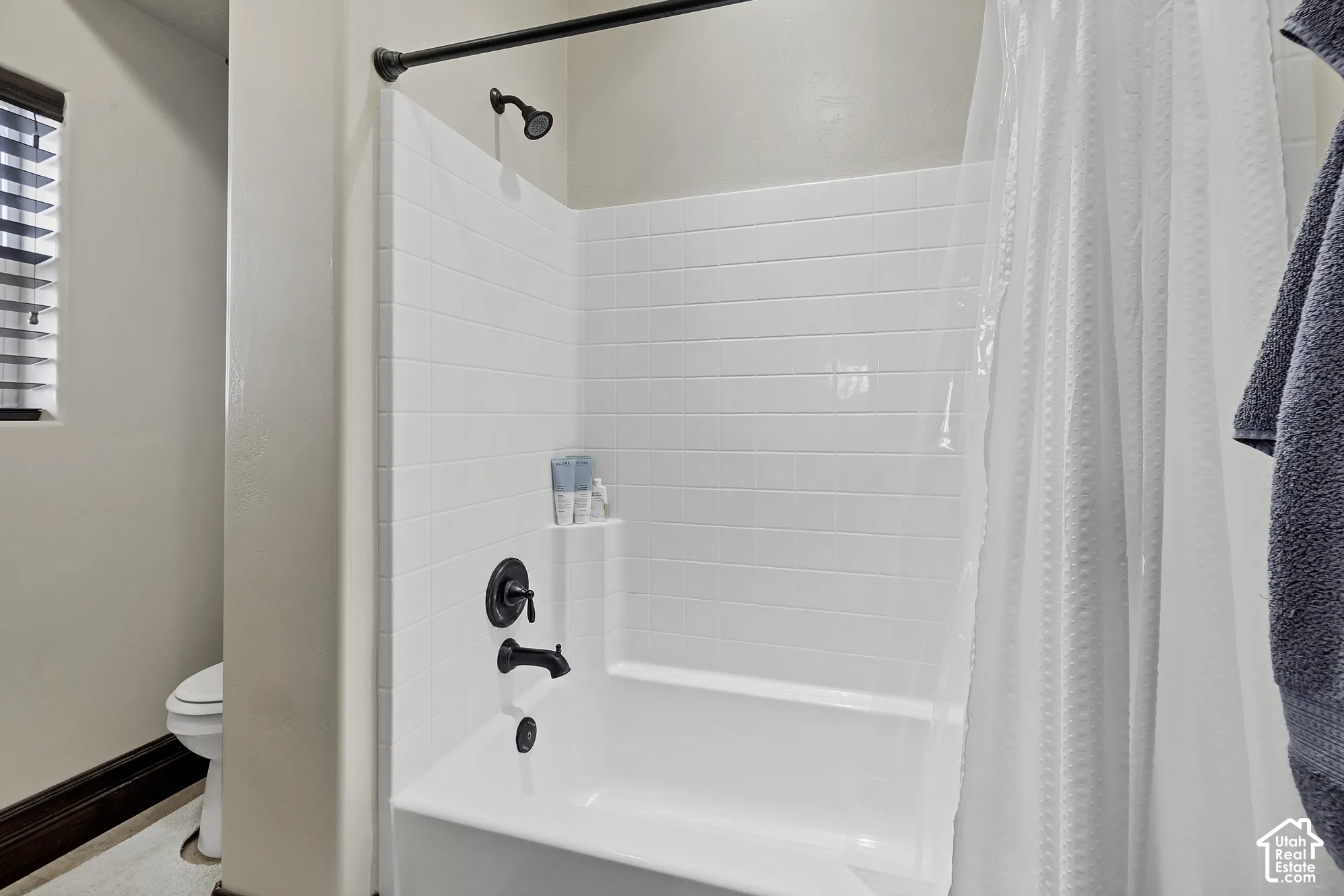White subway tile shower surround with a built-in shelf, dark bronze fixtures, and a white bathtub