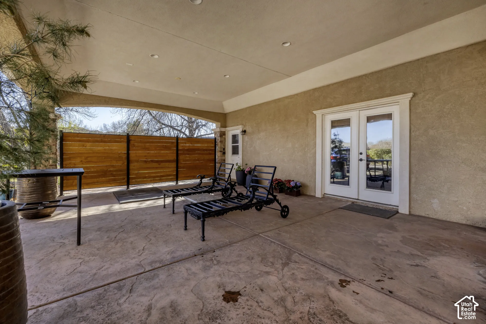 Covered outdoor patio featuring stamped concrete flooring, recessed lighting, and a wood privacy fence