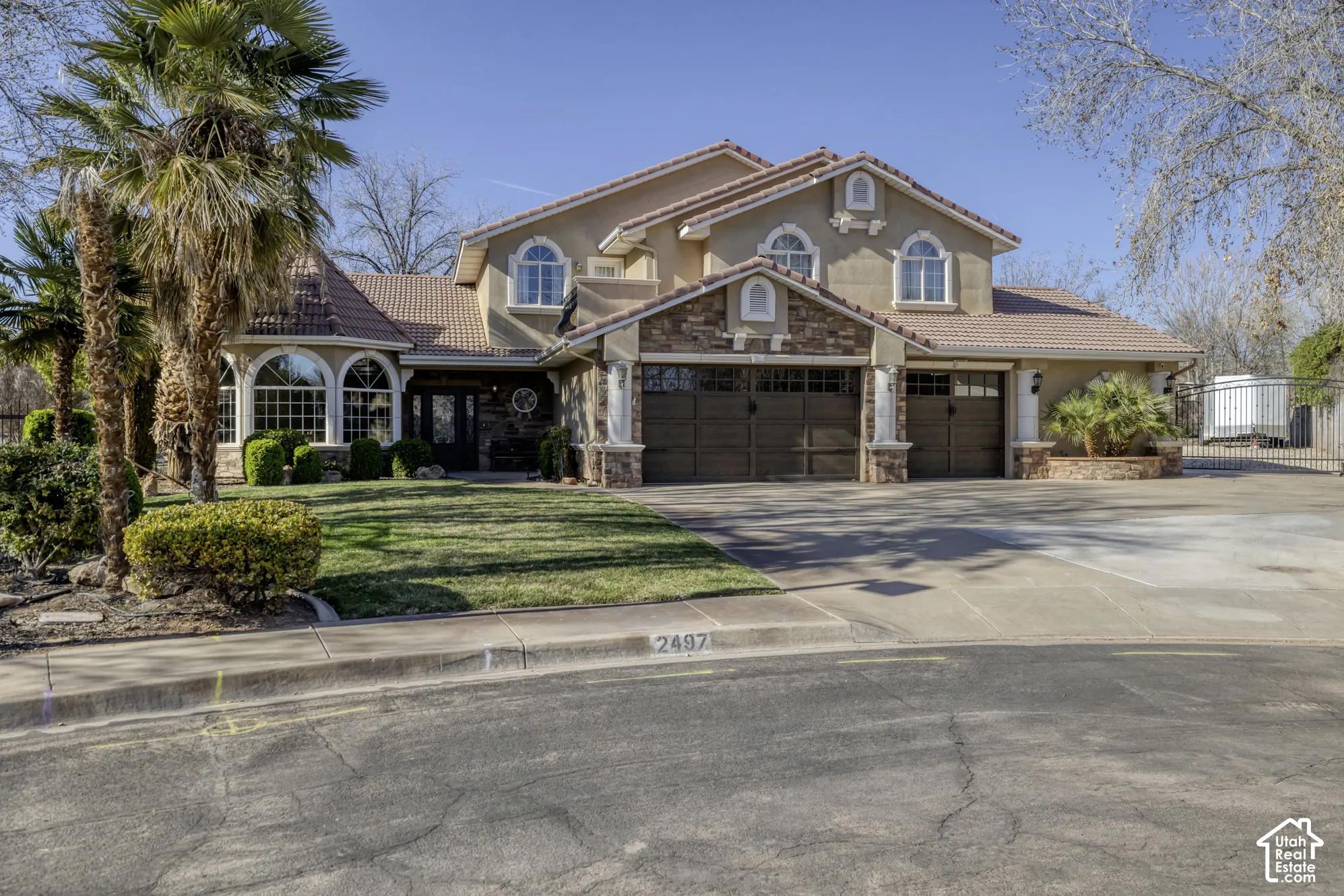 Stucco and stone exterior with arched windows, a multi-car garage, and a tiled roof