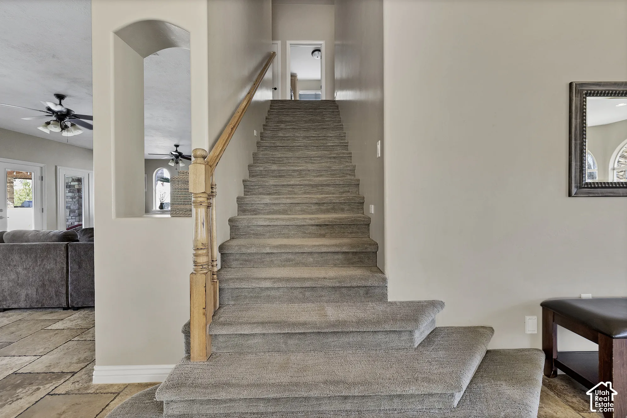 Carpeted staircase featuring a natural wood handrail and banister