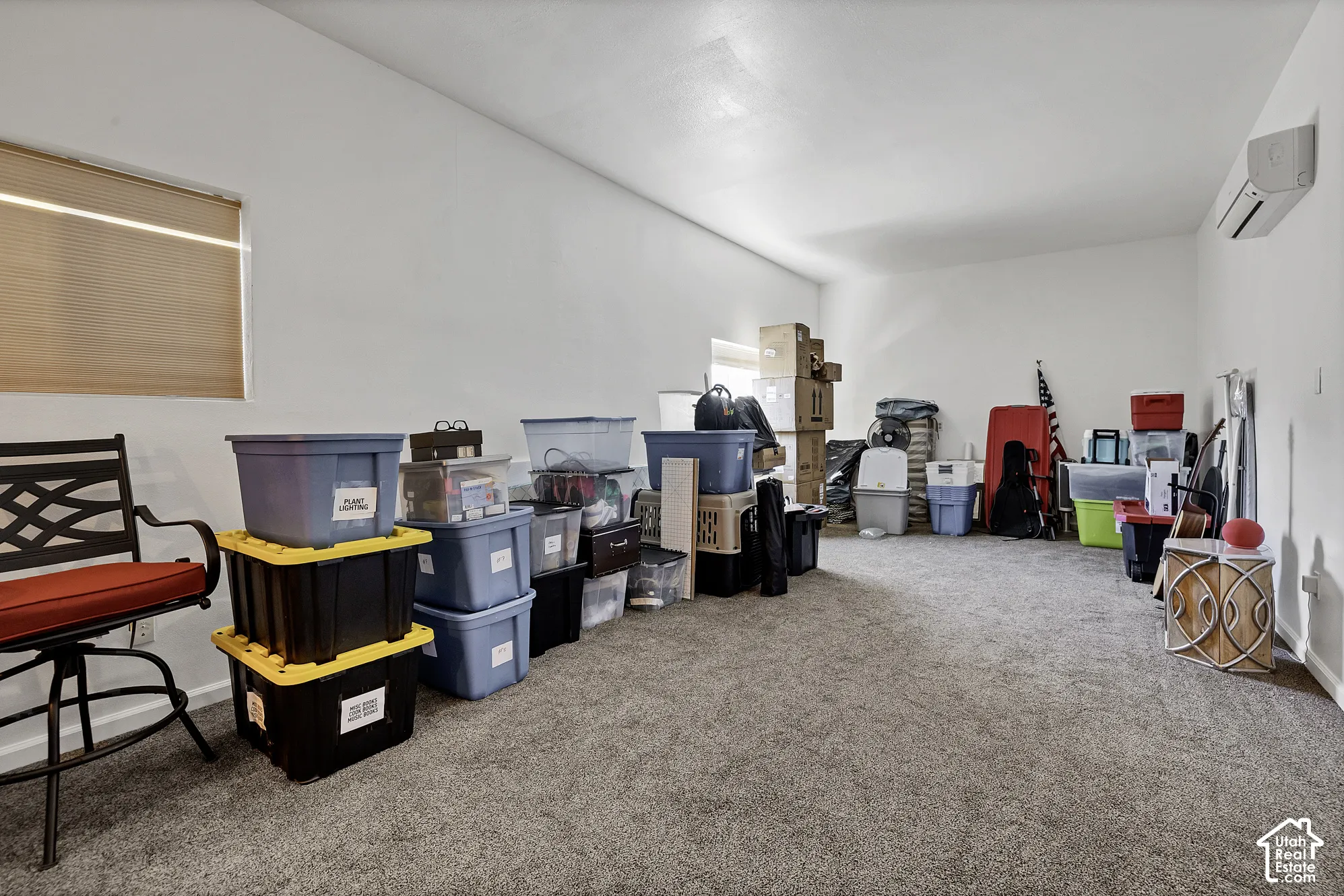 Carpeted room with a window, window blinds, and a wall-mounted air conditioning unit
