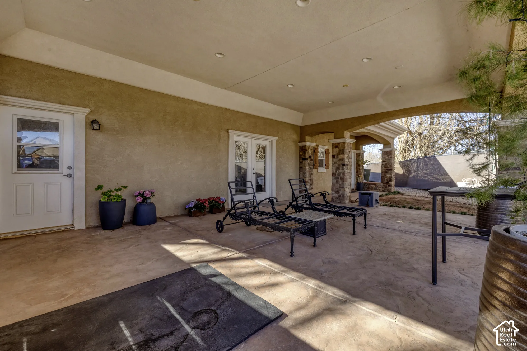 Covered patio with a concrete surface, stone-clad columns, and recessed lighting