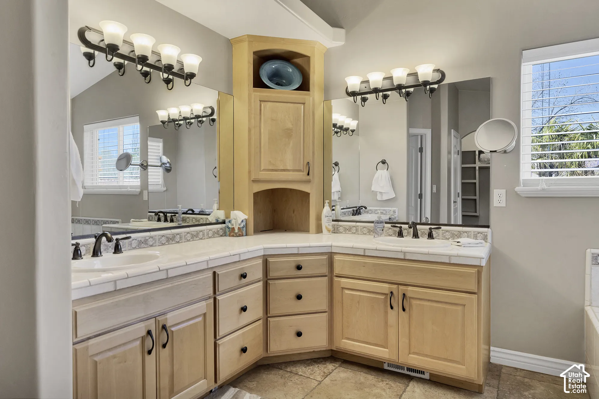 Dual vanity with light wood-finish cabinetry, tile countertops, and integrated sinks