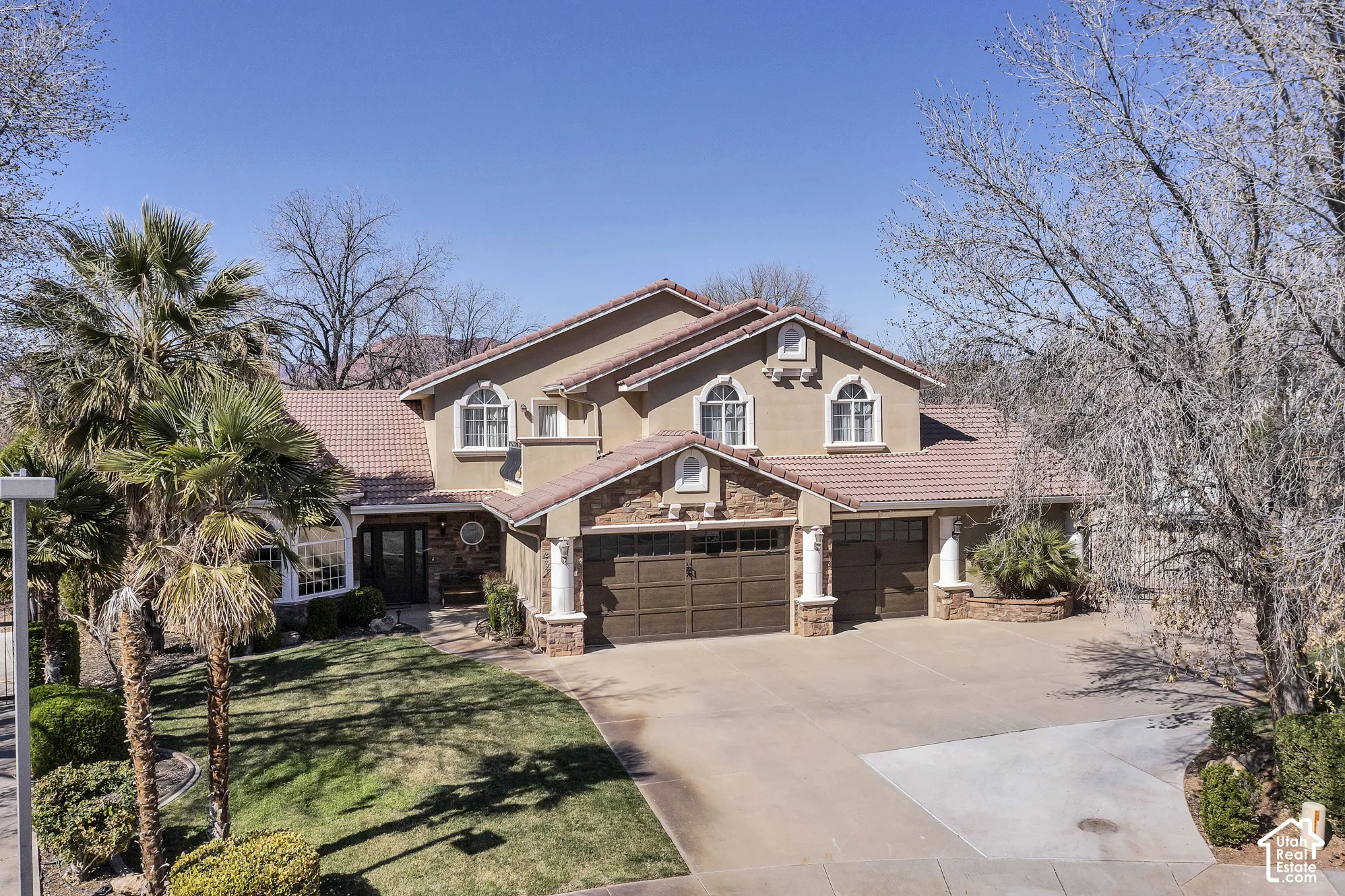 Stucco exterior with stone accents, arched windows, tile roof, and a multi-car garage