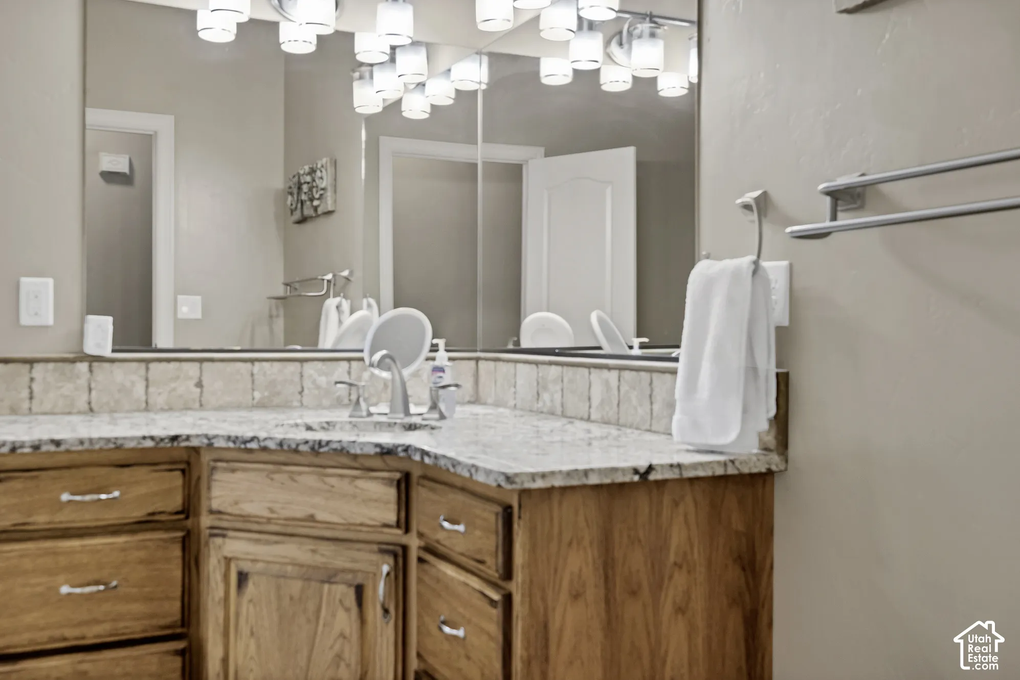 Wood-finish vanity with multiple storage drawers, light-toned countertop, and undermount sink