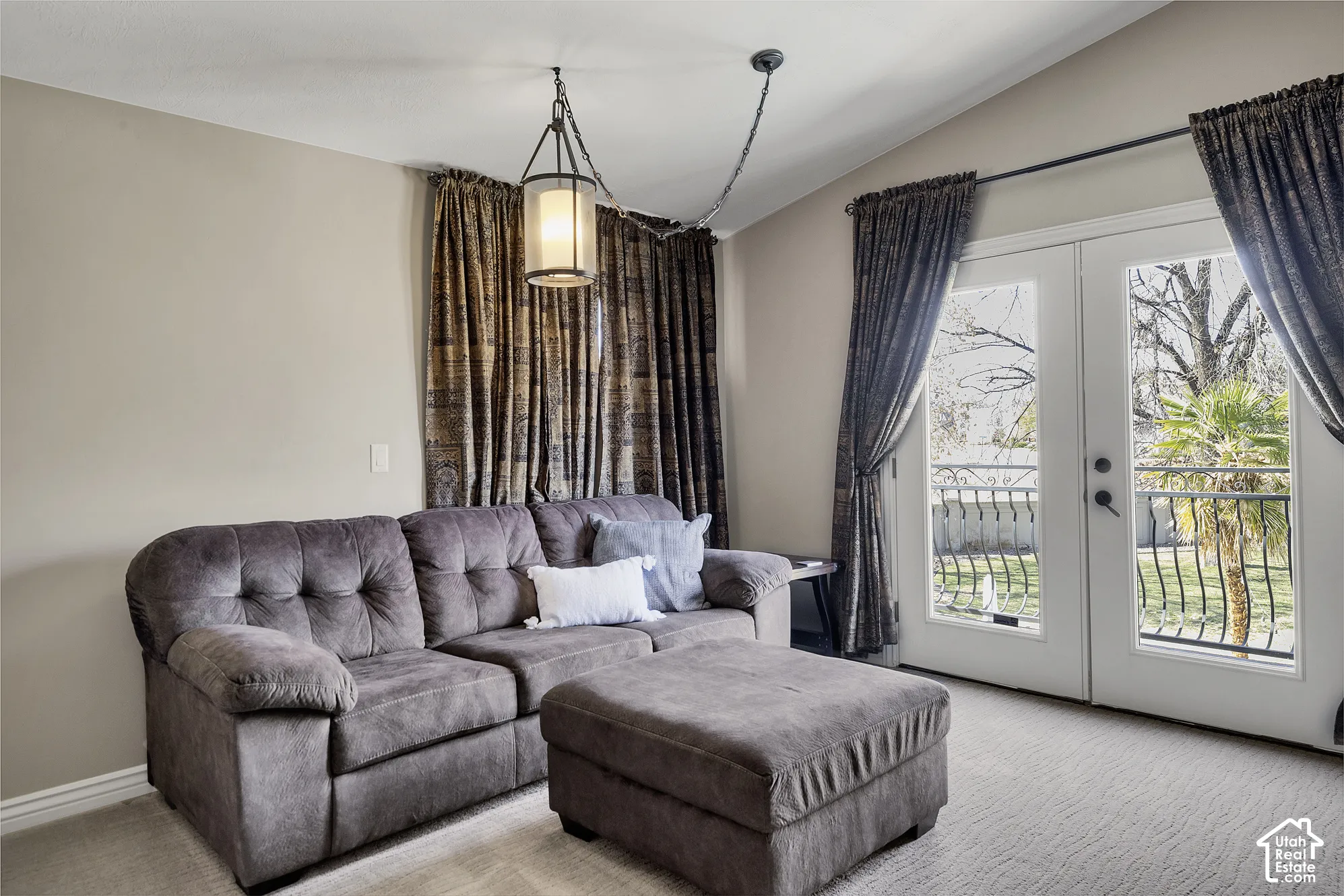 Vaulted ceiling with an attached pendant light fixture, French doors with an exterior balcony, and light-colored wall paint