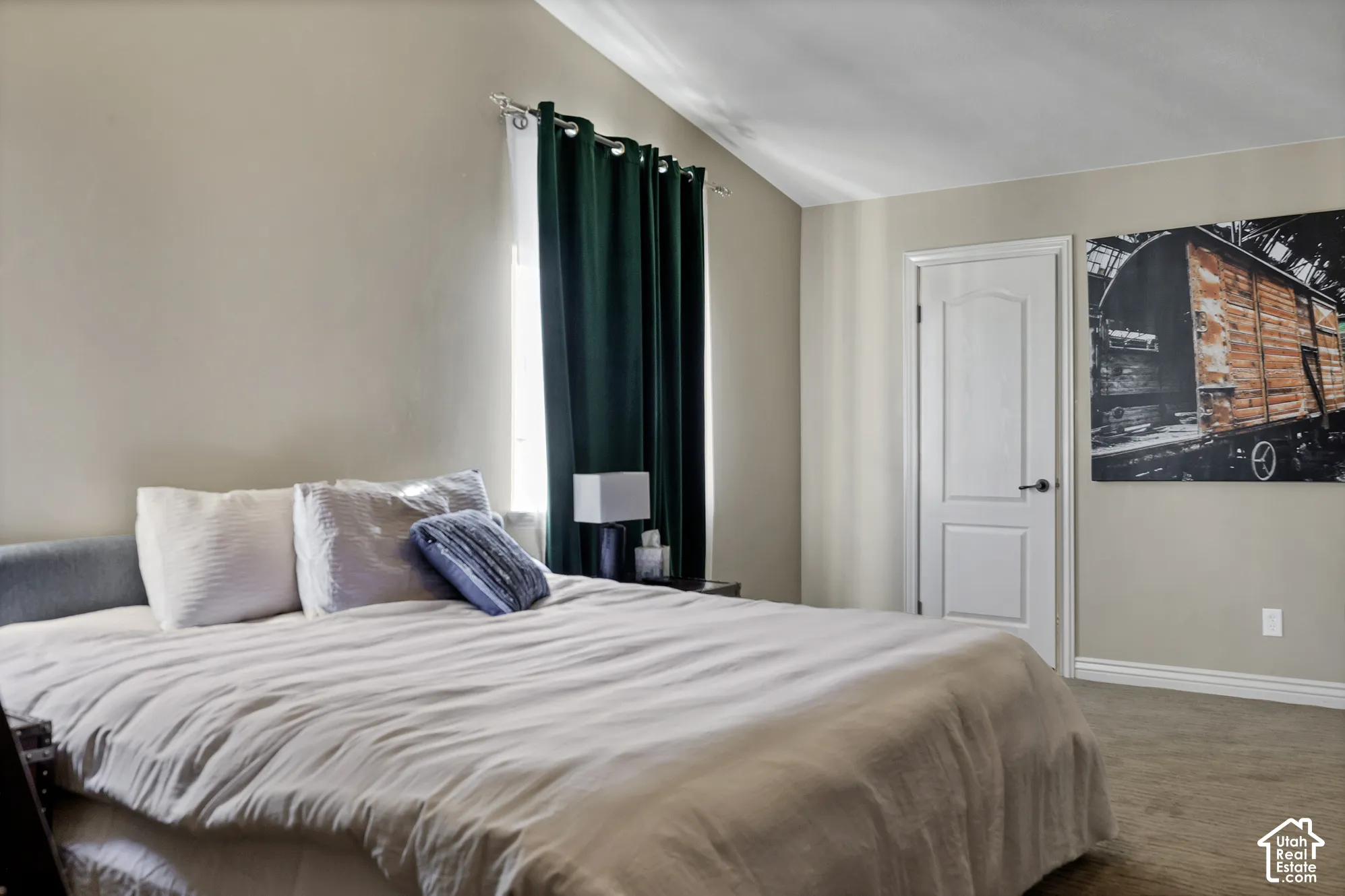 Vaulted ceiling, neutral wall paint, white interior door, dark hardware, light-toned carpet flooring