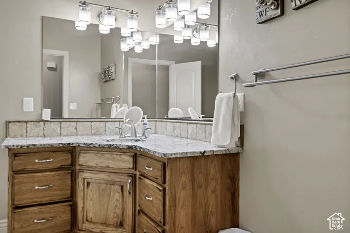 Wood-finish cabinetry with silver-tone hardware, a light-toned stone countertop, and a tiled backsplash