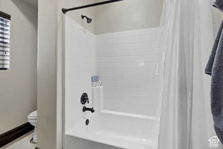 White subway tile shower surround with a built-in shelf, dark bronze fixtures, and a white bathtub