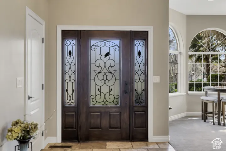 Entryway featuring a wood-finish door with decorative glass and wrought iron detailing, flanked by two sidelights