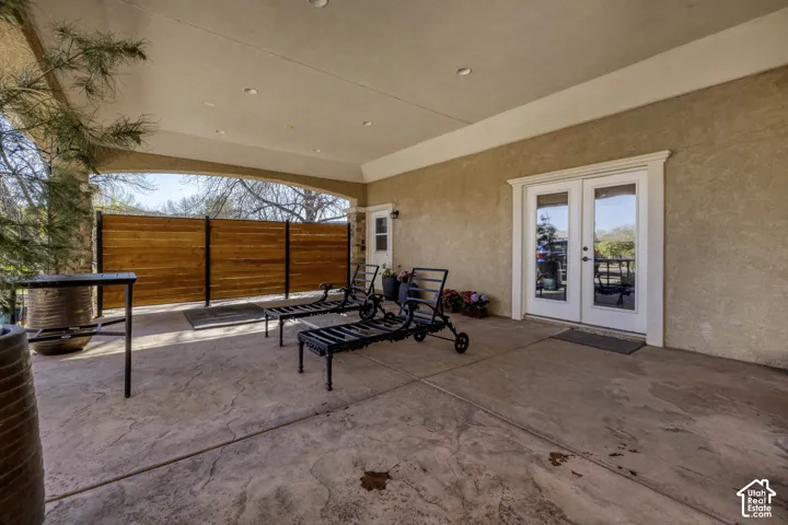 Covered outdoor patio featuring stamped concrete flooring, recessed lighting, and a wood privacy fence
