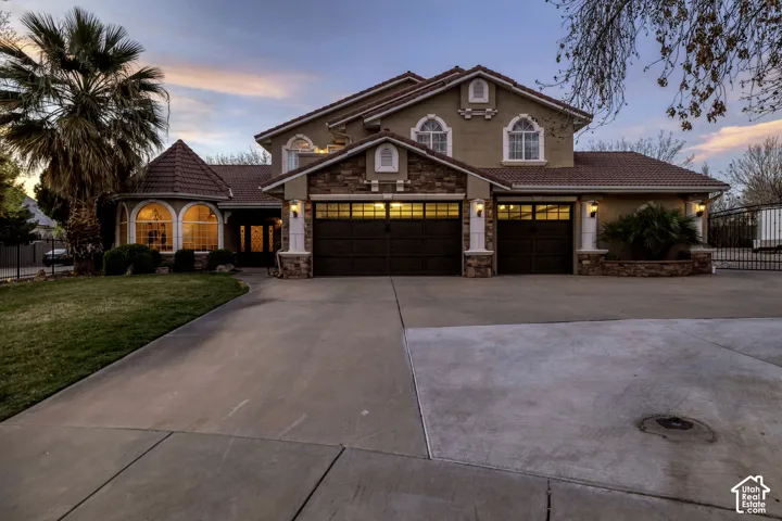 Stucco exterior with stone accents, arched windows, covered entry, and a multi-car garage with carriage-style doors
