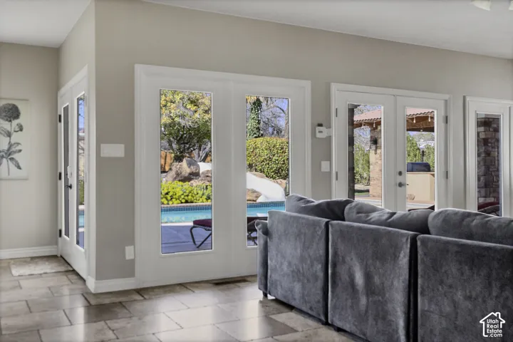 Expansive tile flooring, multiple sets of French doors, and a swimming pool with rock landscaping