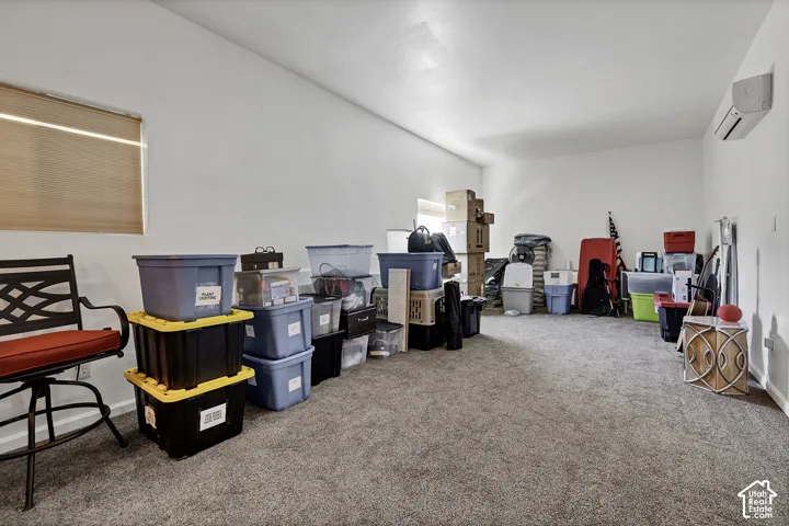 Carpeted room with a window, window blinds, and a wall-mounted air conditioning unit