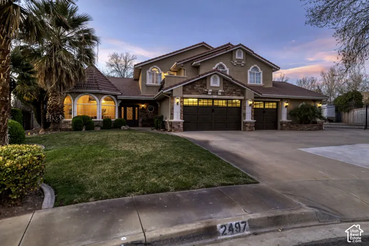 Stucco exterior with stone accents, arched windows, and a multi-car garage