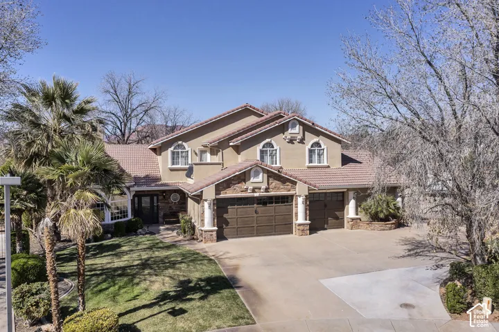 Stucco exterior with stone accents, arched windows, tile roof, and a multi-car garage