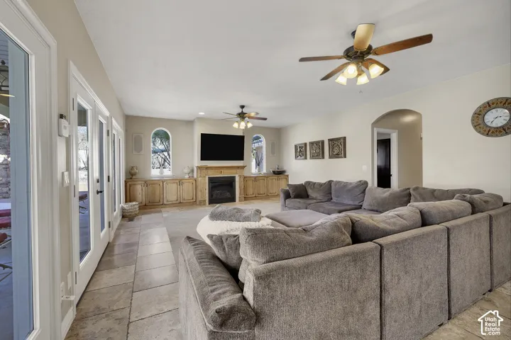 Spacious living area featuring tile flooring, multiple French doors, a built-in entertainment center with a fireplace, and arched wall openings