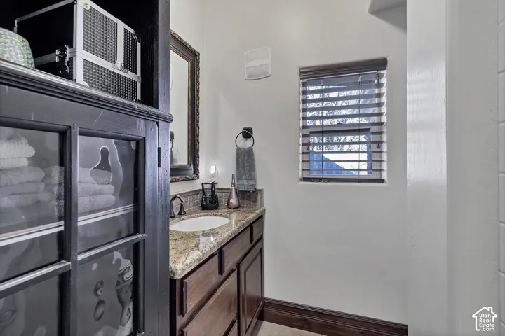 Vanity with integrated sink, stone-finish countertop, dark wood-finish cabinetry, and oil-rubbed bronze faucet