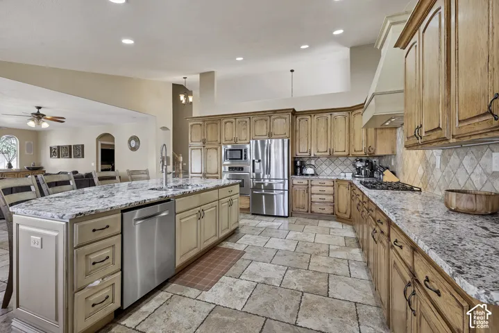 Kitchen featuring a central island with a granite countertop, stainless steel appliances, extensive wood cabinetry, tile flooring, and a tile backsplash