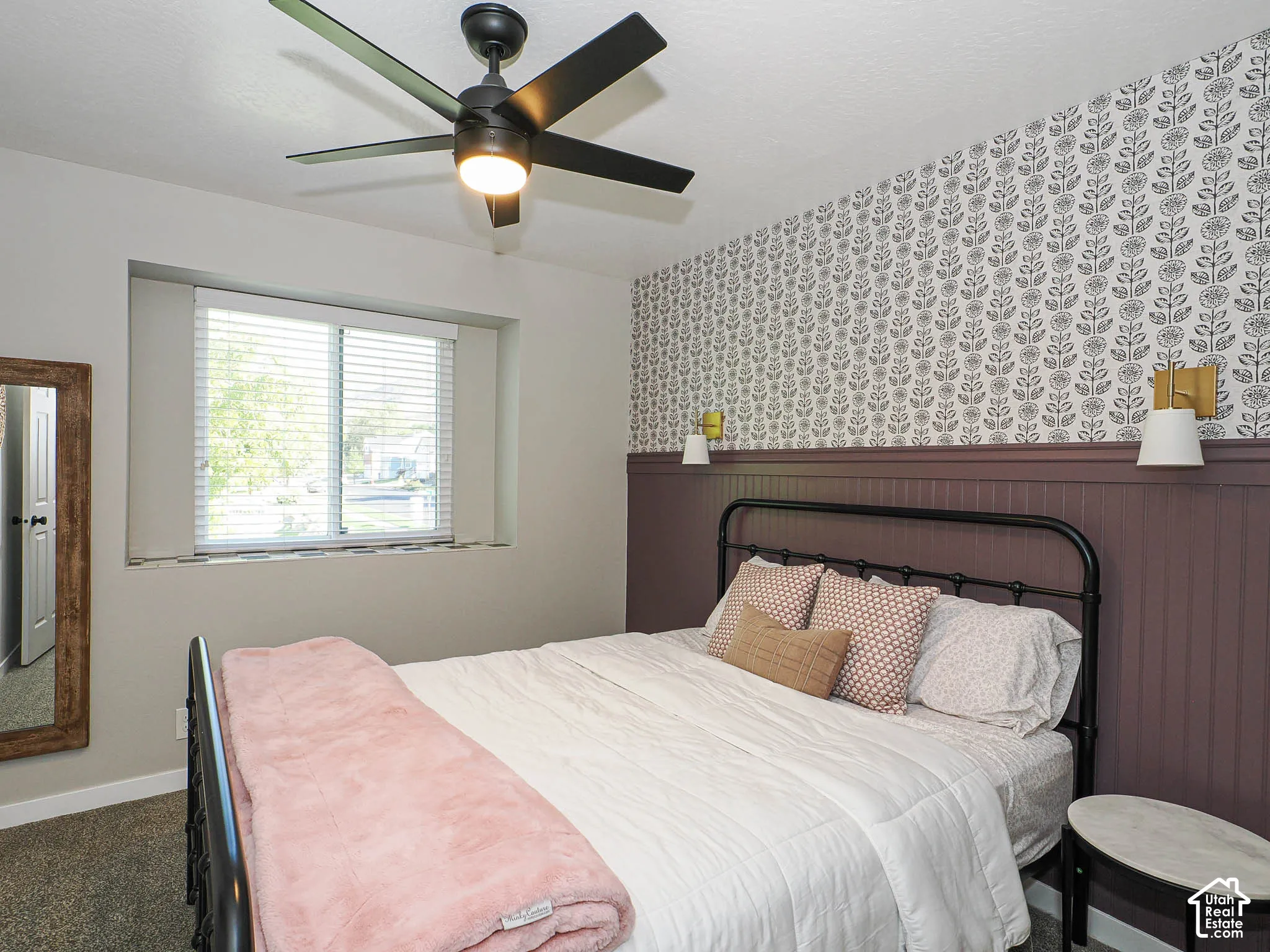 Decorative accent wall with patterned wallpaper and wainscoting, recessed window with blinds, and a ceiling fan with integrated lighting