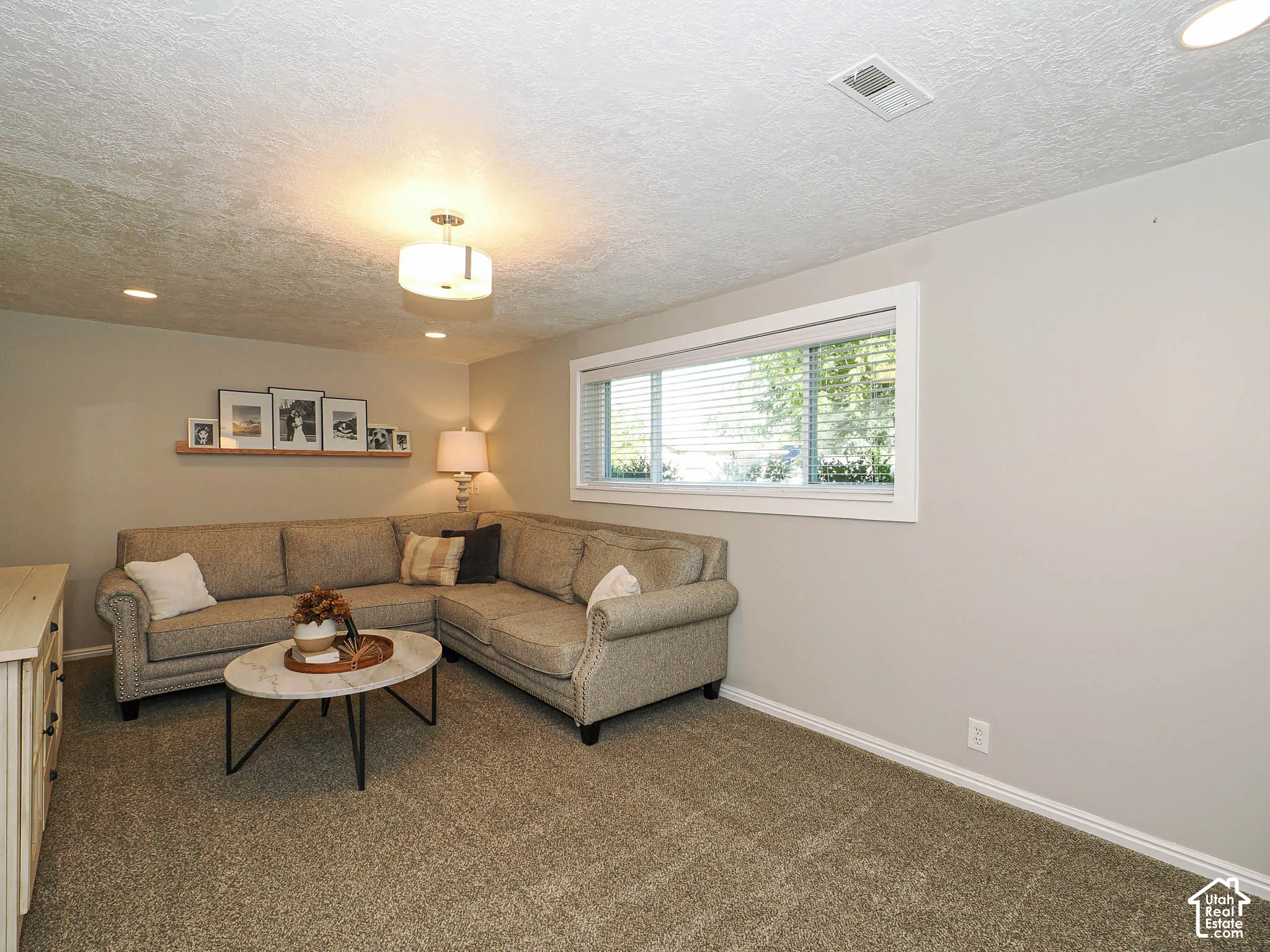Recessed lighting complemented by a central flush-mount fixture, neutral paint throughout, and a window with white trim
