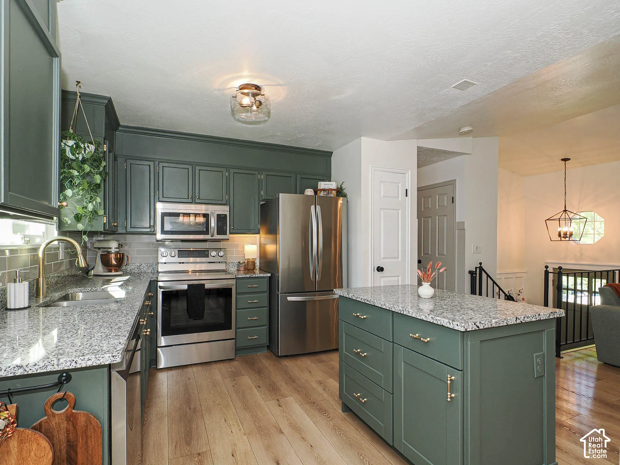 Kitchen featuring granite countertops, stainless steel appliances, wood-finish flooring, a kitchen island, and custom cabinetry