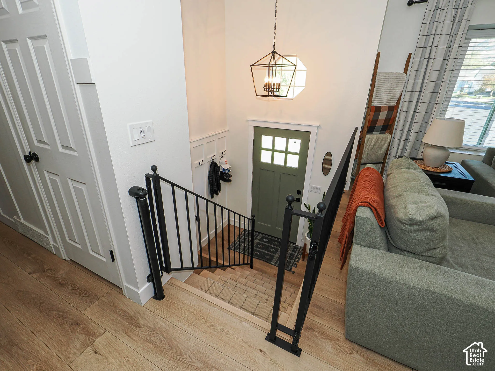 Wood-finish flooring, a contemporary black metal stair railing, and a geometric pendant light fixture