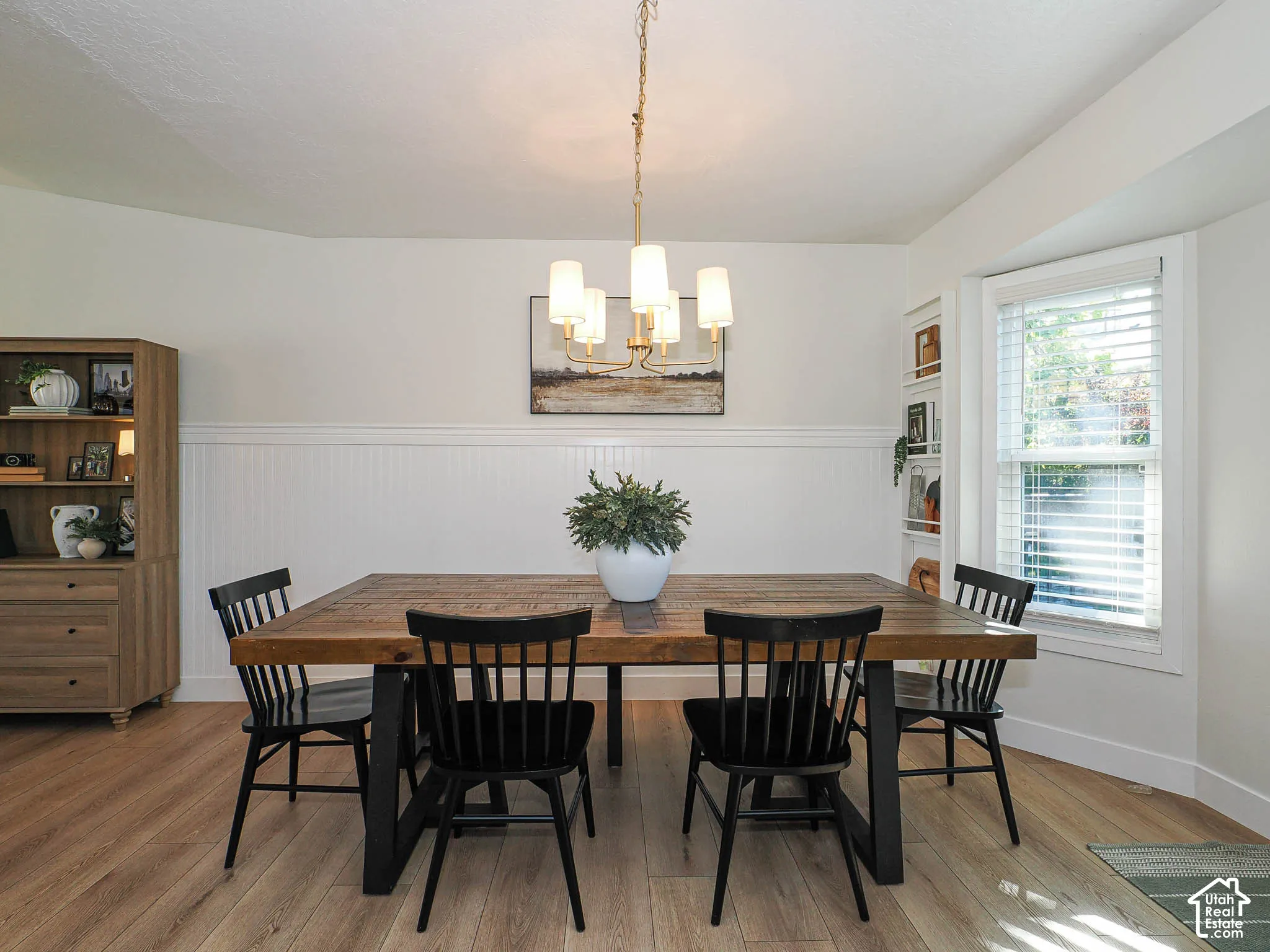 Wood-finish flooring, wainscoting details, built-in shelving, recessed window, and overhead lighting fixture