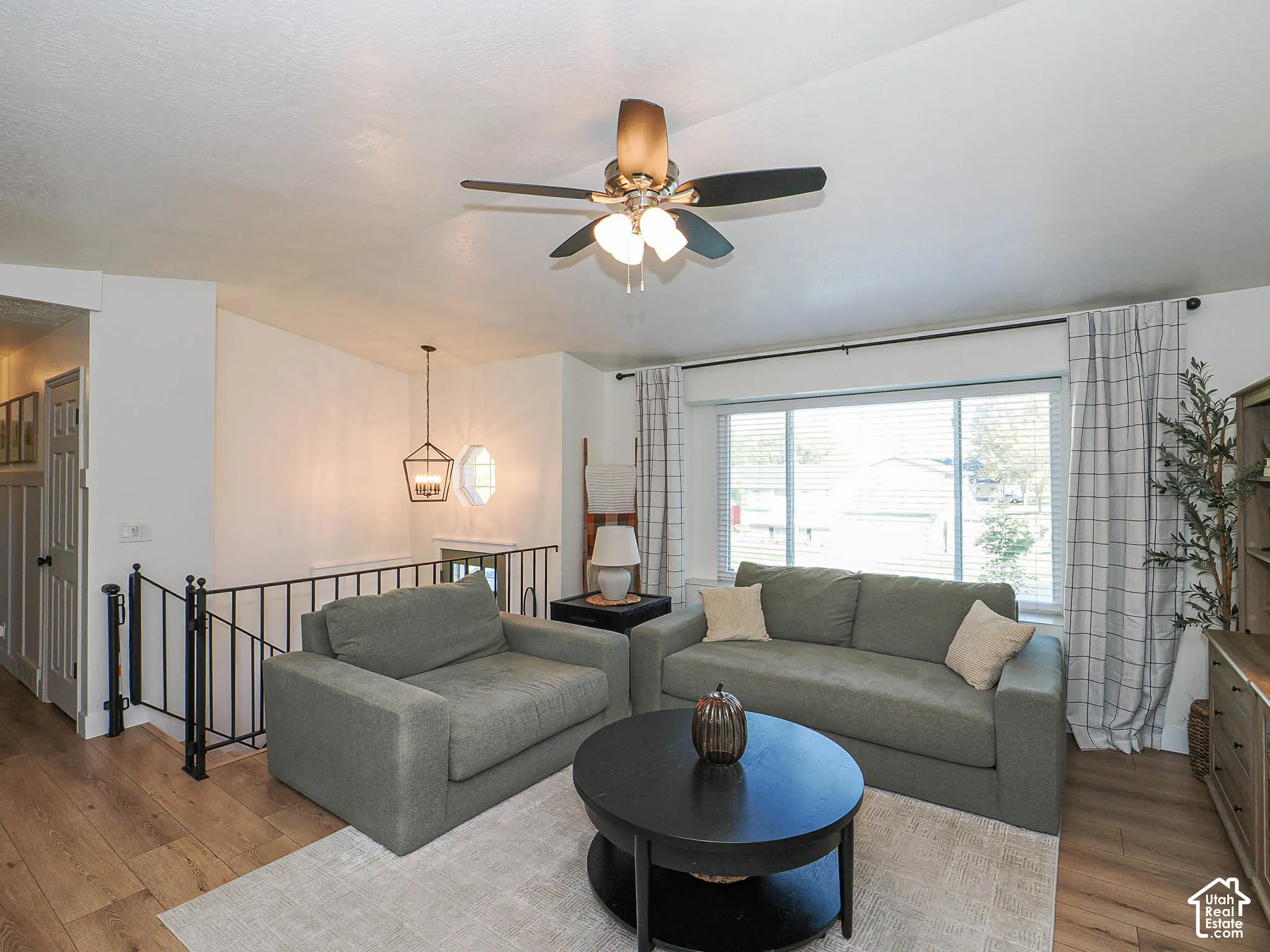 Spacious living area featuring wood-finish flooring, a ceiling fan, and a large window
