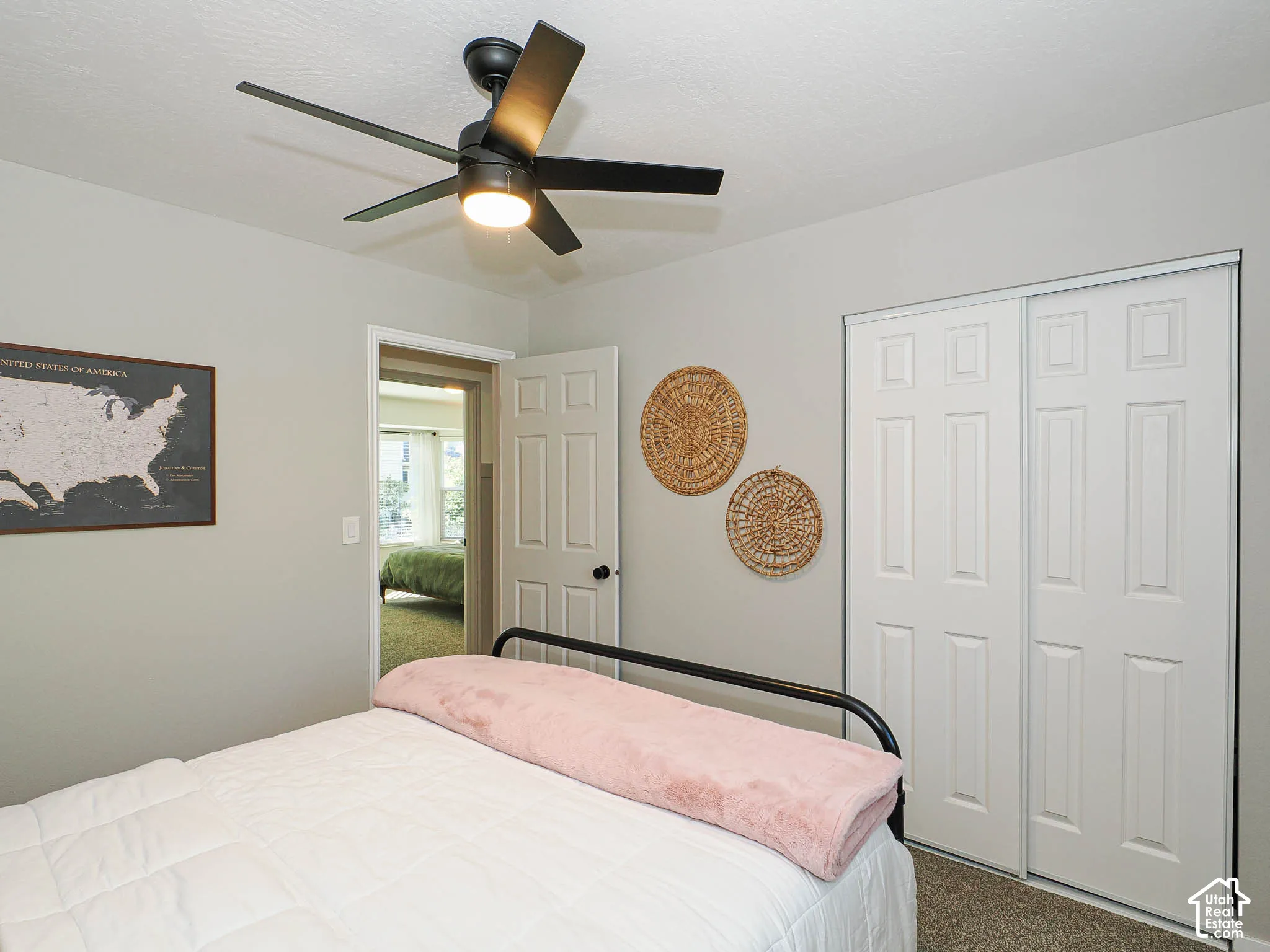 Ceiling fan with integrated lighting, neutral wall paint, white bi-fold closet doors, wall-to-wall carpeting