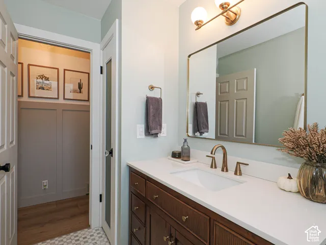 Vanity featuring a white countertop with an undermount sink, brass-finish faucet, and a large framed mirror with integrated lighting