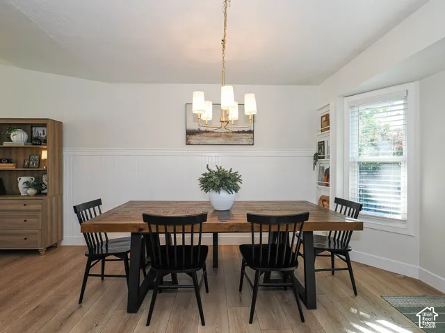 Wood-finish flooring, wainscoting details, built-in shelving, recessed window, and overhead lighting fixture