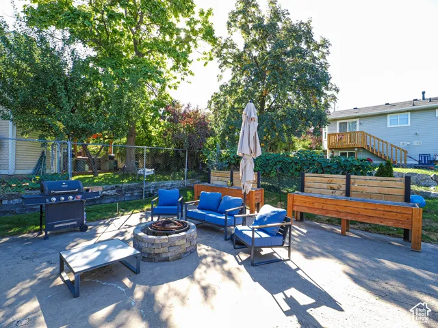 Concrete patio featuring a stone-finish fire pit, built-in wooden planters, and mature trees