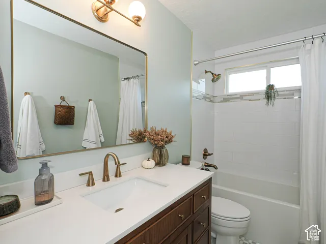 White countertop, integrated sink, bronze-finish faucet, wood-finish vanity, and overhead lighting fixture