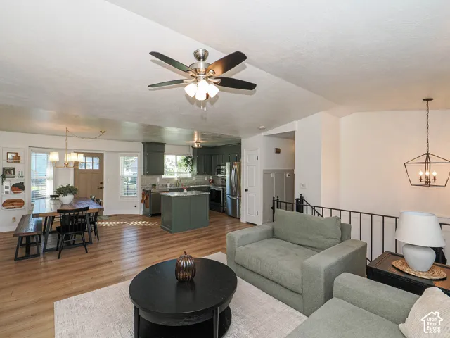 Wood-finish flooring throughout, kitchen with dark cabinetry and stainless steel appliances, open concept layout, and a dining area with a chandelier