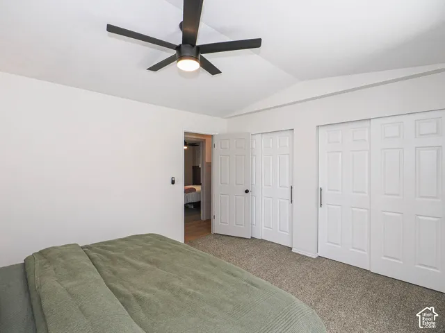 Angled ceiling with a contemporary black ceiling fan, white paneled bifold closet doors, and neutral carpeting