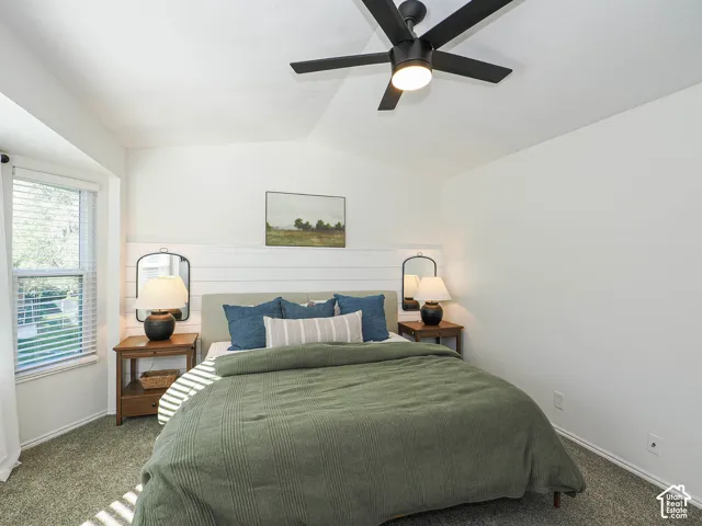 Vaulted ceiling, ceiling fan with integrated lighting, shiplap accent wall, window with blinds, and carpet flooring
