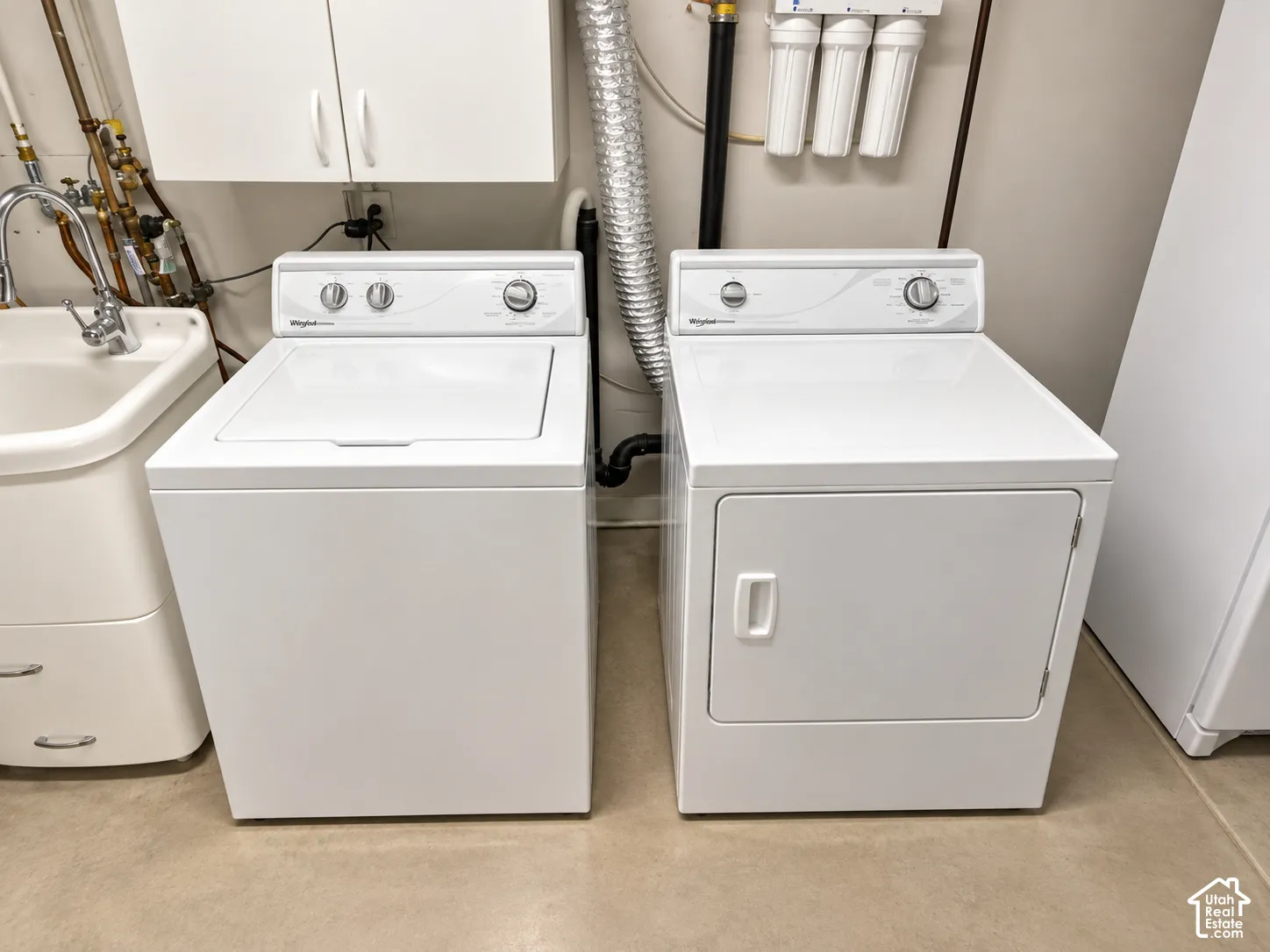 Laundry area featuring a top-load washing machine, front-load dryer, and utility sink