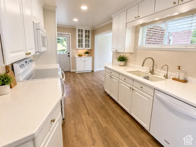 White cabinetry, light-toned countertops, wood-finish flooring, stainless steel sink, and recessed lighting