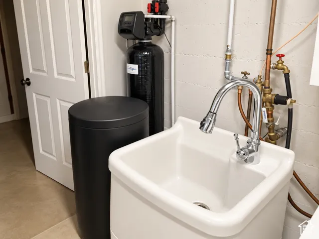 Utility sink with a chrome pull-down faucet, accompanied by a water conditioning system