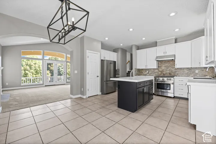 Kitchen featuring stainless steel appliances, white cabinetry, and a dark-toned island with a light-colored countertop