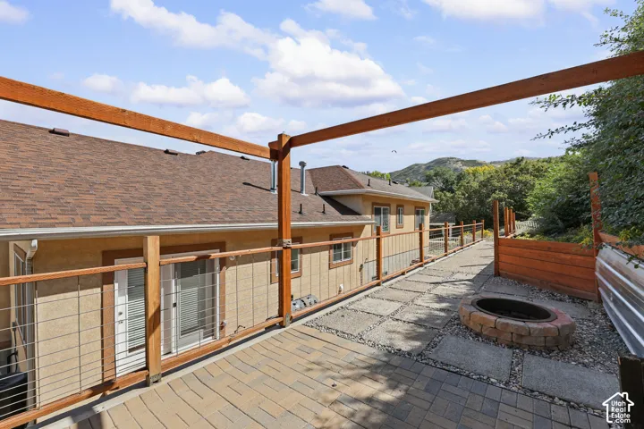 Patio featuring a fire pit, paver and stone pathways, wood-framed railing with cable infill, and a wood pergola frame