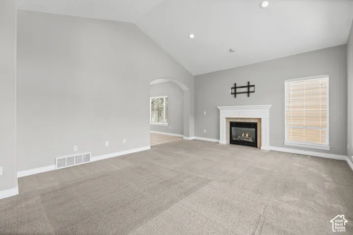 Vaulted ceiling, gas fireplace with classic mantel, recessed lighting, and an arched doorway